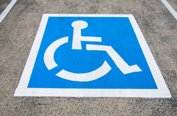 Parkplatzschild für Behinderte reserviert. Behindertenparkplatz mit weiß-blau lackiertem Schild für Behindertenparkplätze. Behindertenparkplatz, blaues Quadrat auf Asphalt. Barrierefreiheitskonzept. - Foto, Bild