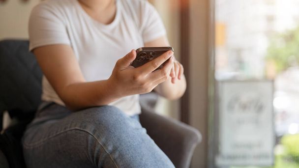 Imagen de cerca de una mujer usando su teléfono inteligente mientras está sentada en una cafetería. chat, texto, mensaje, aplicación móvil. Conceptos de personas y tecnología - Foto, imagen