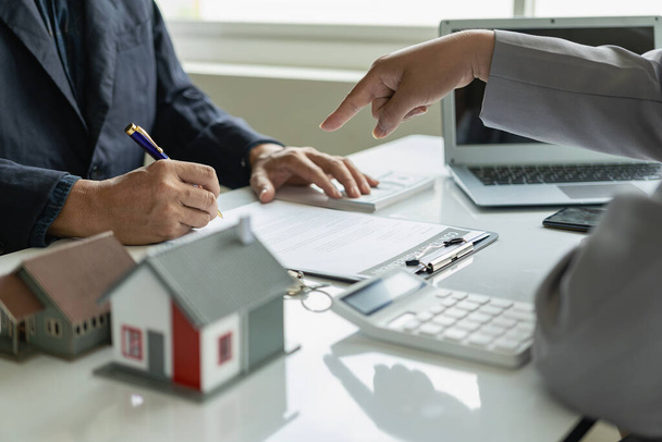 Der Immobilienmakler bildet mit dem Makler ein Haus und der Kunde bespricht den Vertrag zum Kauf, zur Unterzeichnung oder zum Darlehen von Immobilien. Fernbedienung - Foto, Bild