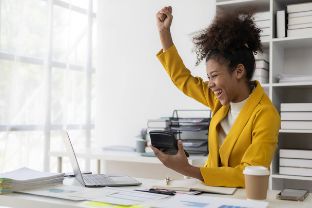 Hombre de negocios afroamericano recibe buenas noticias, celebra el éxito con el brazo en frente de la computadora portátil en el escritorio, feliz mujer afroamericana emocionada celebra la victoria sentado en el coworking  - Foto, Imagen