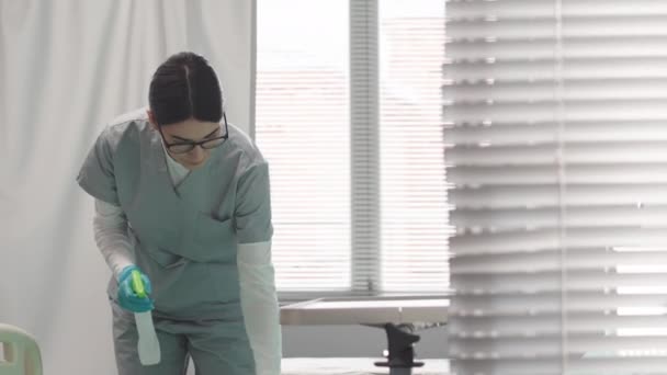 Jonge blanke verpleegkundige schoonmaken ziekenhuis afdeling, steriliseren bed en andere oppervlakken met antiseptische - Video
