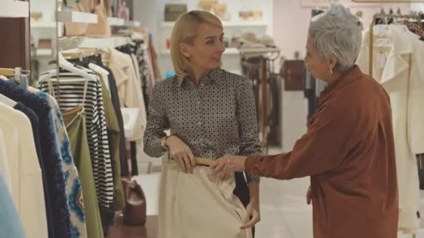Shop consultant helpt vrouwelijke klant om elegante outfit te kiezen in designer kleding winkel - Video