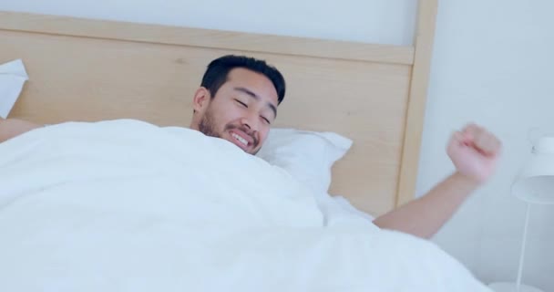 Happy man, bed and wake up in morning with yawn and stretching ready to start the day at home. Male person awake in happiness or satisfaction for good sleep or rest in daily bedroom routine in house. - Footage, Video