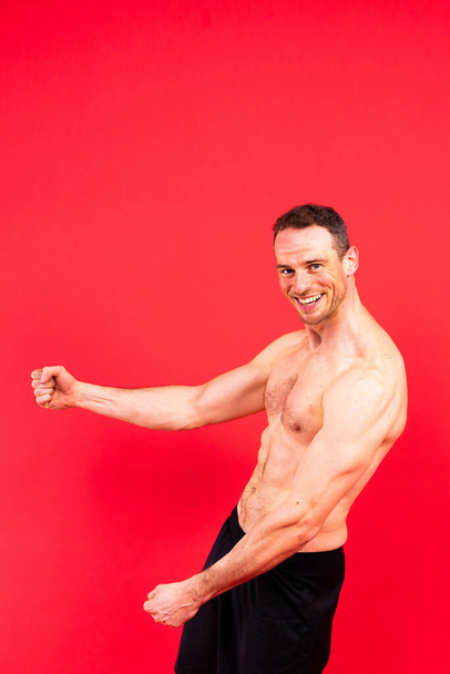 Homem atleta isolado em um fundo preto, vermelho, branco. Motivação física. - Foto, Imagem