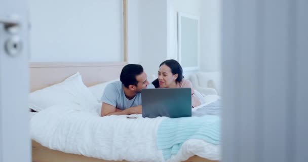 Couple, laptop and talking on bed for love, watch movies and relax for streaming multimedia. Happy woman, man and conversation in bedroom with computer, social media subscription and online shopping. - Footage, Video