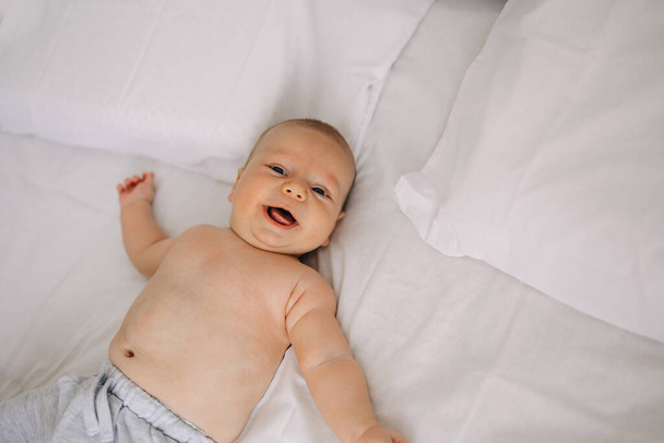Glückliches Neugeborenes liegt auf weißem Laken - Foto, Bild