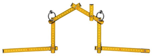 Orange and yellow wooden folding ruler in the shape of a house with steel rings for hanging. Isolated on white background. Photography. - Photo, Image