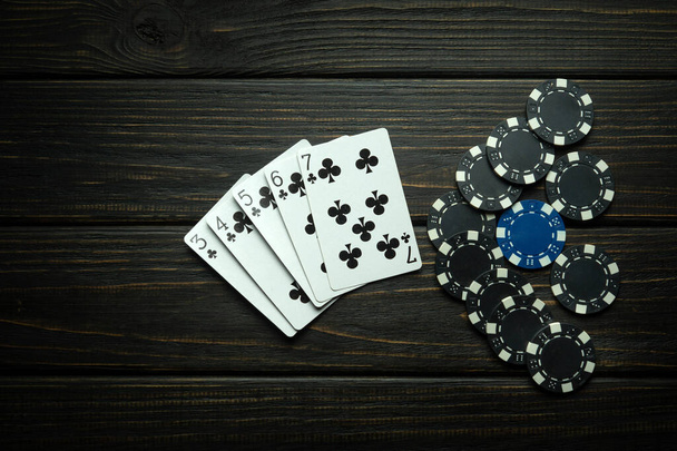 Populares juego de póquer con escalera combinación ganadora. Tarjetas con fichas en una mesa vintage negra en un club de poker. Espacio negro gratuito para anuncios. - Foto, imagen