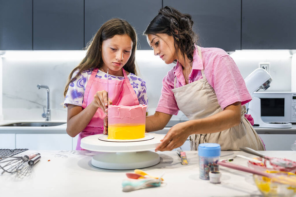 Famille cuisinière. Mère et fille colorent le gâteau. - Photo, image