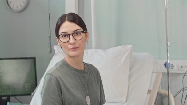 Талия портрет белой женщины-солдата, смотрящей в камеру, сидя на больничной койке - Кадры, видео