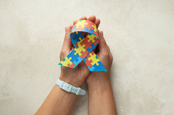 Cinta con rompecabezas multicolores sobre un fondo claro. Concepto del Día Mundial del autismo - Foto, imagen