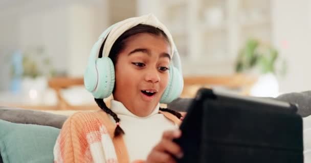 Home, happy and girl with headphones, tablet or connection with video games, excited or app. Person, kid or child with technology, headset or entertainment with fun, playing online or streaming music. - Footage, Video