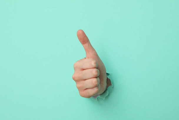 Female hand showing thumb up on turquoise background - Photo, Image