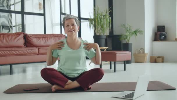 Yaşlı kadın evde yoga egzersizi yapıyor. Olgun bir kadın internetten meditasyon yapmadan önce ısınır. Yüksek kalite 4k görüntü - Video, Çekim
