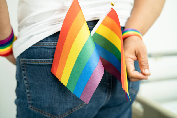 Femme tenant le drapeau coloré de l'arc-en-ciel LGBT, symbole de lesbiennes, gays, bisexuels, transgenres, droits humains, tolérance et paix. - Photo, image