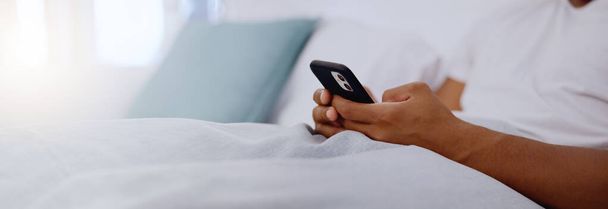 Typing, bed and hands of a man with a phone for social media, communication and chat. Contact, internet and guy scrolling on a mobile app for messages, reading emails or notification in the bedroom. - Foto, Bild