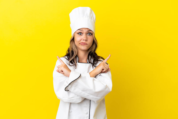 Nuori venäläinen kokki tyttö eristetty keltaisella taustalla osoittaa laterals joilla epäilyksiä - Valokuva, kuva