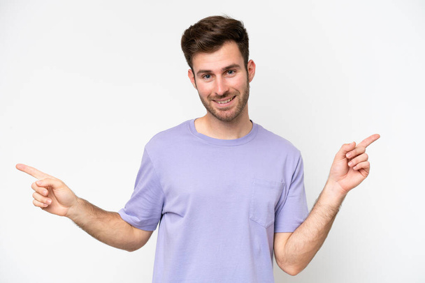 Young caucasian man isolated on white background pointing finger to the laterals and happy - Photo, Image
