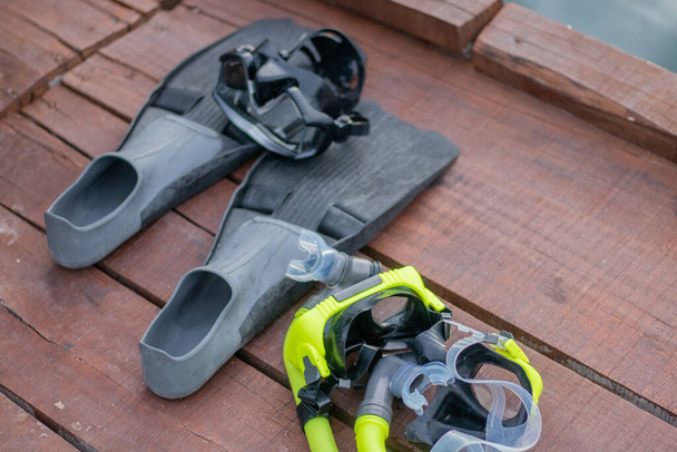 Full set of Scuba Diving equipment with selective focus on wooden pier. Fins, Depth Gauge, Balanced Regulator,Power Inflator, Dive Mask and Snorkel. Scuba gear and accessories. - Photo, Image