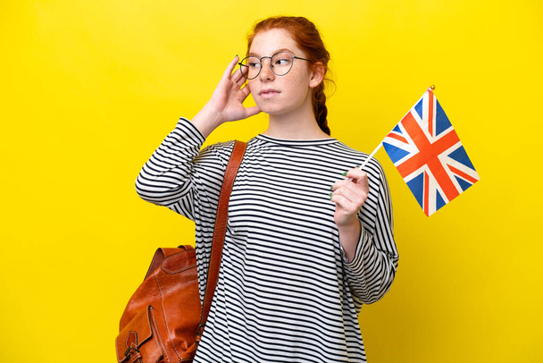 Junge hispanische Frau mit einer britischen Flagge auf gelbem Hintergrund hat Zweifel - Foto, Bild