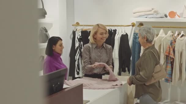 Profesionální prodavačka hovoří o kolekci pletenin prezentované v designérské showroomu k zákazníkovi stojící u pultu - Záběry, video