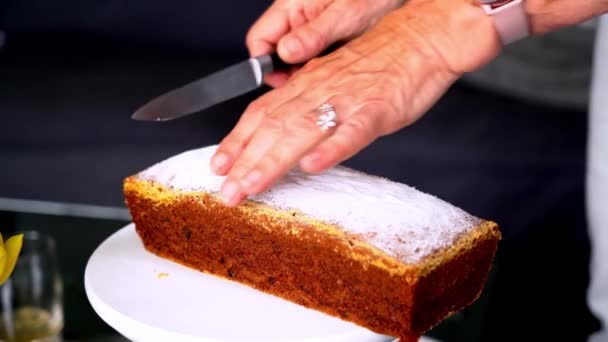 close-up van de handen van een oude vrouw. Oudere vrouw snijdt een stuk heerlijke taart. Snij zoete taart. familievakanties en tradities - Video