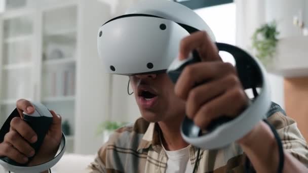Podekscytowany szczęśliwy Afroamerykanin facet grać w wirtualnej rzeczywistości gry w domu wakacje hobby nowoczesne technologie gry w VR okulary kask doświadczenie cyberprzestrzeni metawersum odtwarzanie wideo komputer 3D świat - Materiał filmowy, wideo