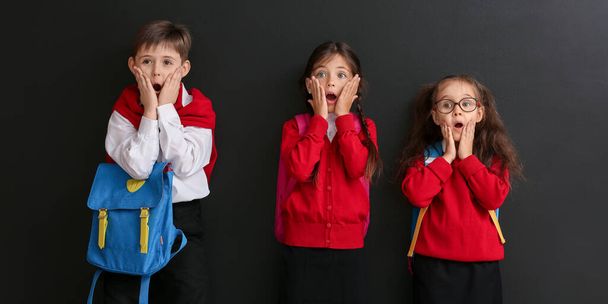 Sorprendidos niños en edad escolar sobre fondo oscuro - Foto, Imagen