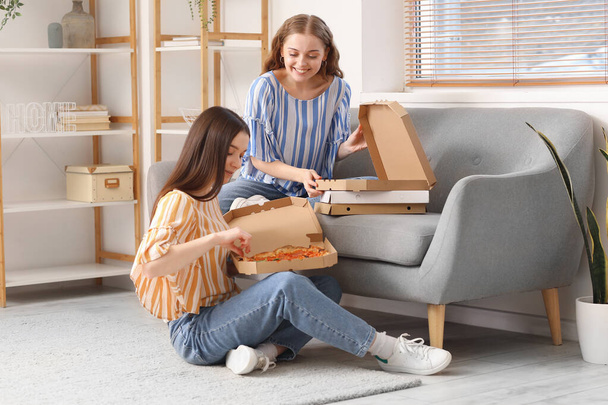 Young women eating tasty pizza at home - Foto, Bild