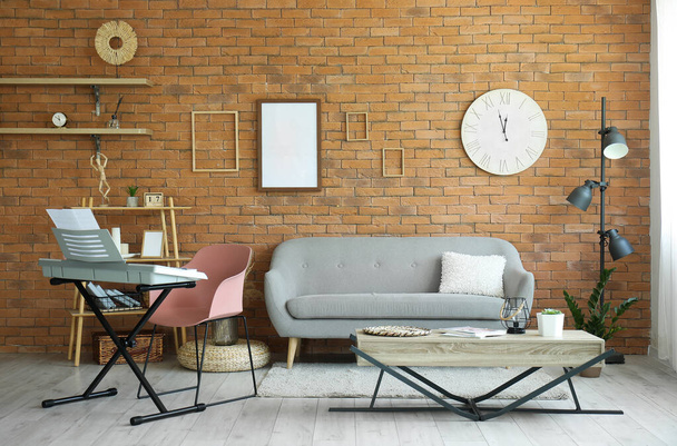 Belső tér elegáns nappali modern szintetizátorral és kanapé ellen téglafal - Fotó, kép