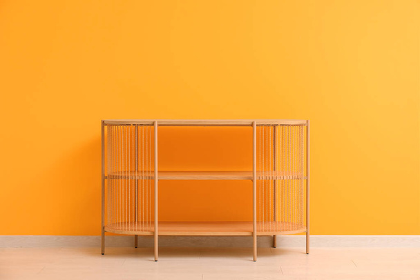 Unidad de estanterías de madera cerca de la pared naranja en la habitación - Foto, imagen