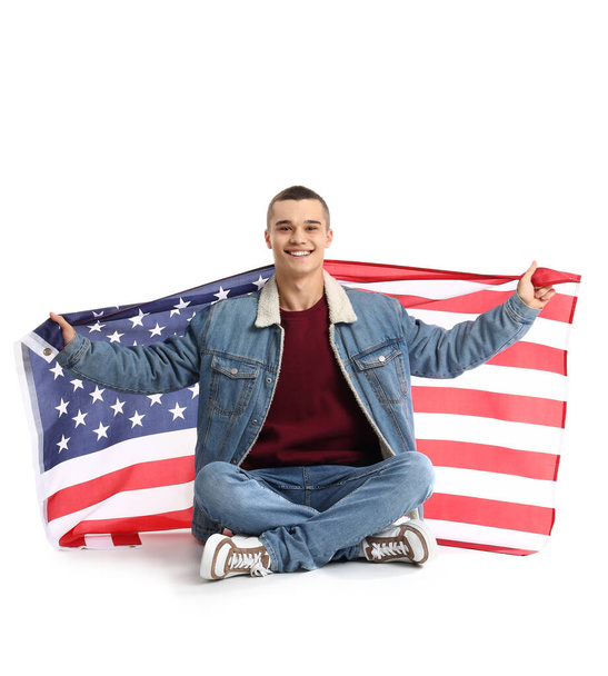 Menino adolescente com bandeira dos EUA sentado no fundo branco - Foto, Imagem