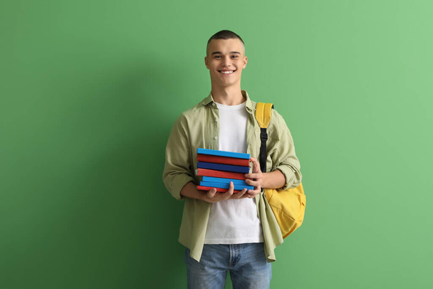 Ευτυχισμένος μαθητής με σακίδιο και βιβλία σε πράσινο φόντο - Φωτογραφία, εικόνα