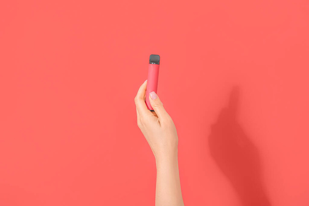 Nő kezében elektronikus cigaretta piros háttér - Fotó, kép