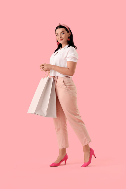 Portrait of happy young woman with shopping bag on pink background - Photo, Image