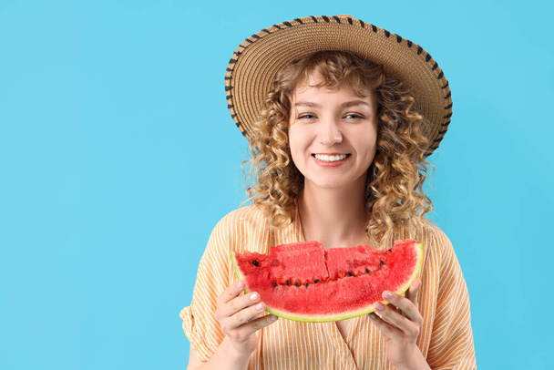 Šťastná krásná mladá žena v proutěný klobouk s plátek čerstvého melounu na modrém pozadí - Fotografie, Obrázek
