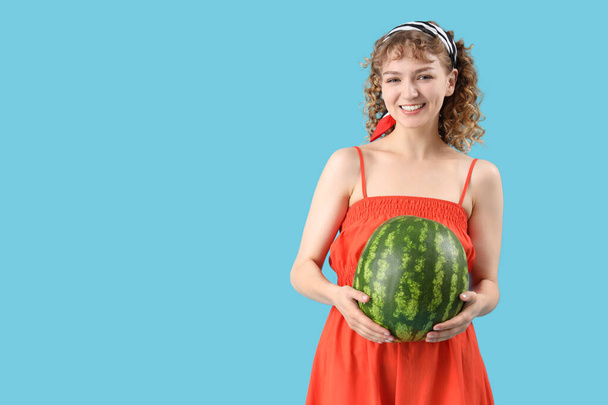 Happy beautiful young woman with ripe watermelon on blue background - Fotografie, Obrázek