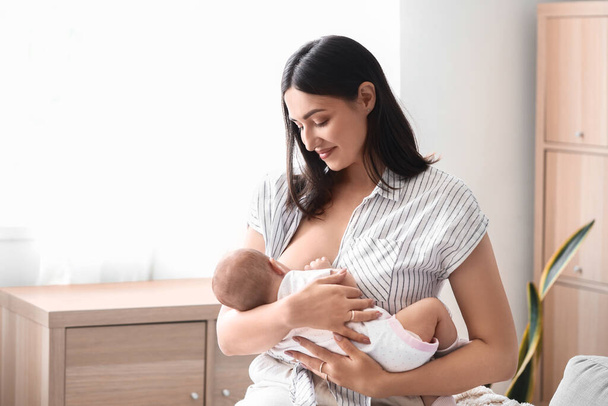 Giovane donna che allatta il suo bambino a casa - Foto, immagini