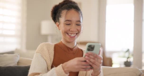 Young woman, phone and laugh on sofa, thinking and relax in home living room for texting, web chat or blog. Girl, excited smile and smartphone with click, meme or social network app on lounge couch. - Felvétel, videó