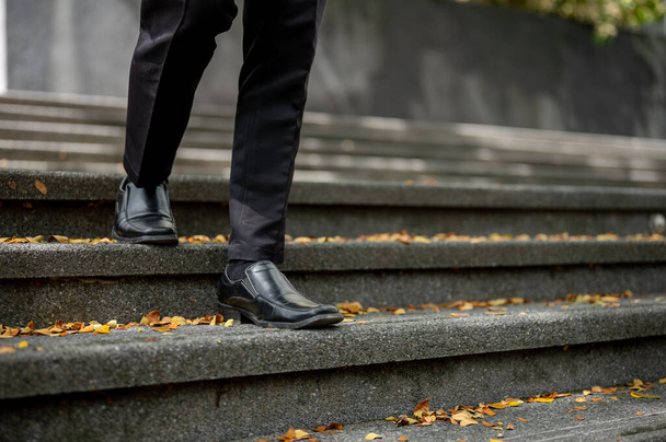 Immagine ritagliata di un uomo d'affari con un completo formale che scende le scale di fronte all'edificio.  - Foto, immagini