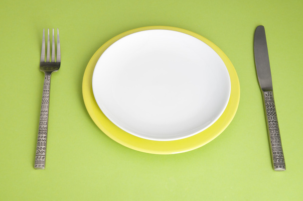 Knife, plates and fork on green background - Foto, immagini