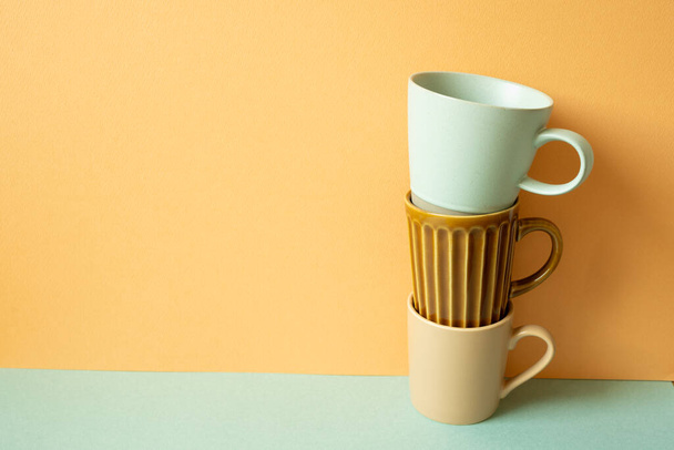 Montón de taza taza en la mesa verde menta. fondo de pared naranja. espacio de copia - Foto, Imagen