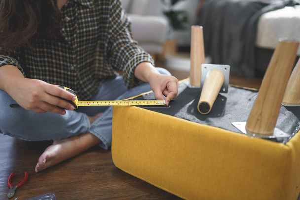 Kadınlar sandalye bacağı montajı için ölçü aletlerini mobilya yaparken ölçmek için kullanırlar. - Fotoğraf, Görsel