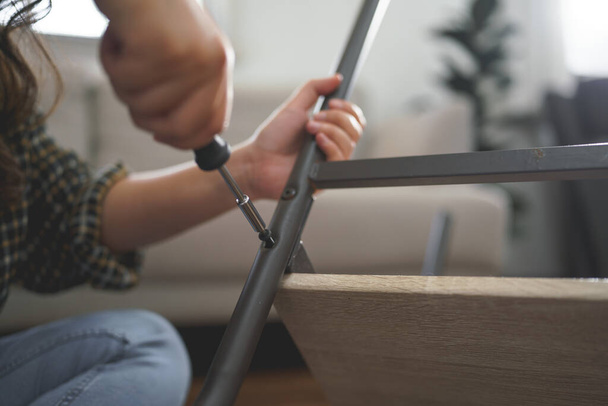 Ženy používají šroubovák k utažení šroubu při opravě nohy židle a výrobě nábytku. - Fotografie, Obrázek
