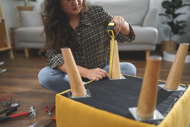 Naiset käyttävät mittanauha laitteiden mittaamiseen pituus tuolin jalka tehdessään käsintehtyjä huonekaluja. - Valokuva, kuva