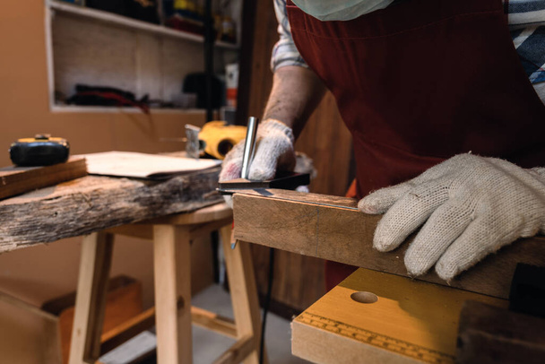 Zamknij rękę stolarza za pomocą narzędzia linijki kąta kwadratowego i ołówka do zaznaczania pozycji na drewnie do cięcia w warsztacie stolarskim. - Zdjęcie, obraz