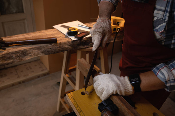 Χειροπρίονο κοπής χειρωνακτικού ξύλου, Κοντινό κόψιμο ξύλου, επιλεκτική εστίαση στον εξοπλισμό πριονόλαμας κατά την εργασία. - Φωτογραφία, εικόνα