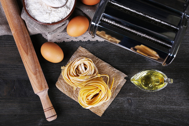 Preparing pasta by pasta machine on rustic wooden background - Fotografie, Obrázek