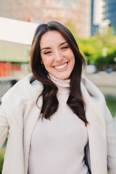 Κάθετη πρόσωπο κοντινό πορτρέτο της καυκάσιας νεαρής γυναίκας χαμογελώντας και κοιτάζοντας κάμερα με τέλεια λευκά δόντια. Όμορφη ευτυχισμένη γυναίκα κοιτάζει μπροστά με θετική και ειλικρινή έκφραση. Υψηλή - Φωτογραφία, εικόνα
