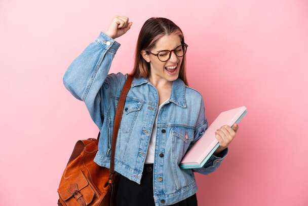 Young caucasian student woman isolated on pink background celebrating a victory - Photo, Image